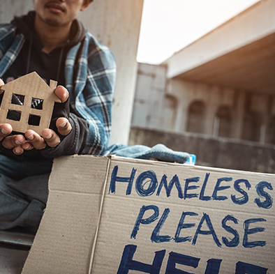 Homeless person holding cutout house with help sign